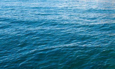 Mavili temiz su dokusu. Okyanusun ve denizin arkaplanı güneşle aydınlanıyor..