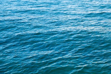 Mavili temiz su dokusu. Okyanusun ve denizin arkaplanı güneşle aydınlanıyor..