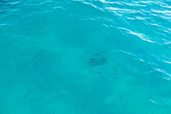 Textura de agua clara en azul. Fondo del océano y el mar retroiluminado por el sol . — Foto de Stock