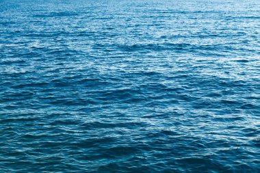Mavili temiz su dokusu. Okyanusun ve denizin arkaplanı güneşle aydınlanıyor..
