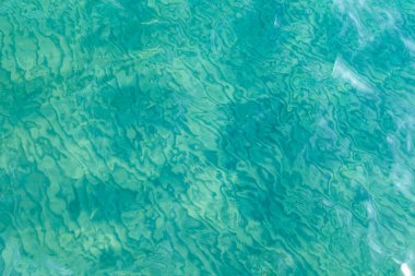 Mavili temiz su dokusu. Okyanusun ve denizin arkaplanı güneşle aydınlanıyor..