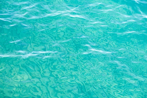 Clear water texture in blue. Background of the ocean and the sea backlit by the sun. — ストック写真