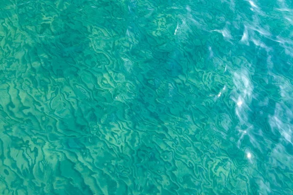 Textura de agua clara en azul. Fondo del océano y el mar retroiluminado por el sol . — Foto de Stock