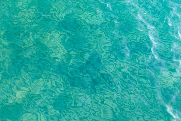 Textura de agua clara en azul. Fondo del océano y el mar retroiluminado por el sol . —  Fotos de Stock