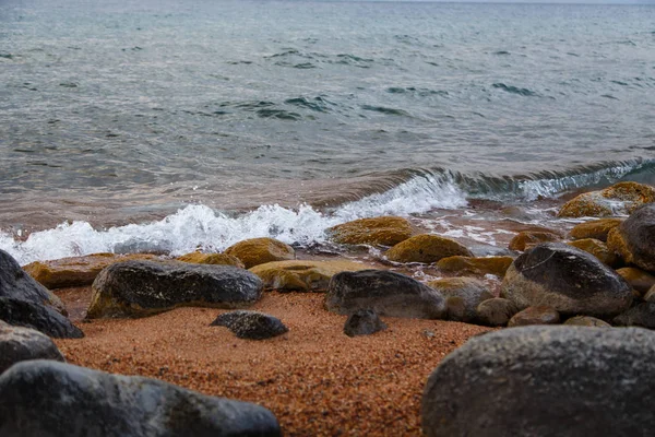 Piedras en la playa del mar. Día de invierno de pastos. Agua clara y arena. Kirguistán, lago Issyk-Kul — Foto de Stock