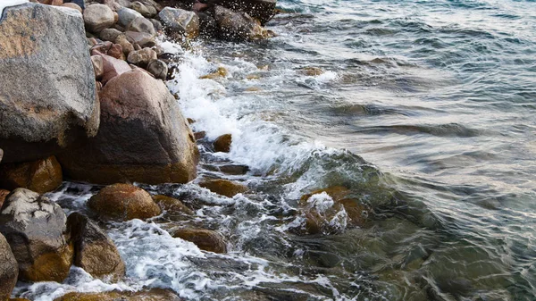 Piedras en la playa del mar. Día de invierno de pastos. Agua clara y arena. Kirguistán, lago Issyk-Kul — Foto de Stock