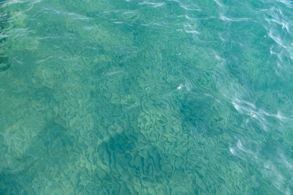 Textura de agua clara en azul. Fondo del océano y el mar retroiluminado por el sol. Agua natural — Foto de Stock