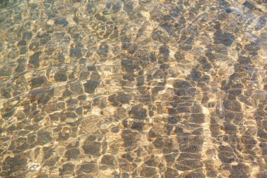 Mavili temiz su dokusu. Okyanusun arka planı ve güneş tarafından aydınlatılan deniz. Doğal su.