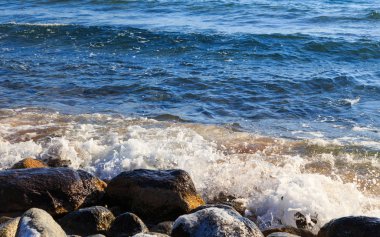 Stones on the sea beach. Pasture winter day. Clear water and sand. Kyrgyzstan, Issyk-Kul Lake