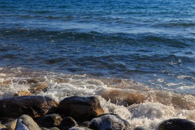 Stones on the sea beach. Pasture winter day. Clear water and sand. Kyrgyzstan, Issyk-Kul Lake