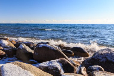 Stones on the sea beach. Pasture winter day. Clear water and sand. Kyrgyzstan, Issyk-Kul Lake