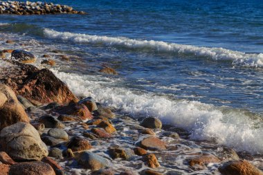 Stones on the sea beach. Pasture winter day. Clear water and sand. Kyrgyzstan, Issyk-Kul Lake