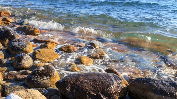 Steine am Meeresstrand. Almwintertag. klares Wasser und Sand. Kyrgyzstan, Issyk-kul-See — Stockfoto