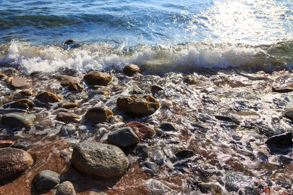 Piedras en la playa del mar. Día de invierno de pastos. Agua clara y arena. Kirguistán, lago Issyk-Kul — Foto de Stock