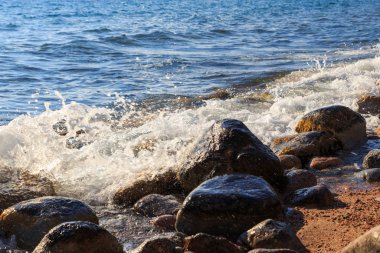 Stones on the sea beach. Pasture winter day. Clear water and sand. Kyrgyzstan, Issyk-Kul Lake