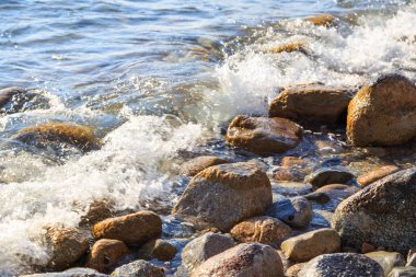 Stones on the sea beach. Pasture winter day. Clear water and sand. Kyrgyzstan, Issyk-Kul Lake