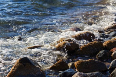 Stones on the sea beach. Pasture winter day. Clear water and sand. Kyrgyzstan, Issyk-Kul Lake