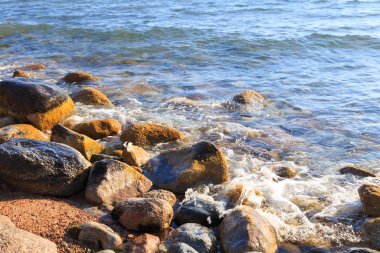 Stones on the sea beach. Pasture winter day. Clear water and sand. Kyrgyzstan, Issyk-Kul Lake