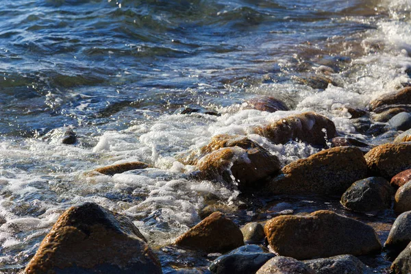 Piedras en la playa del mar. Día de invierno de pastos. Agua clara y arena. Kirguistán, lago Issyk-Kul — Foto de Stock