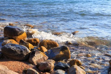 Stones on the sea beach. Pasture winter day. Clear water and sand. Kyrgyzstan, Issyk-Kul Lake