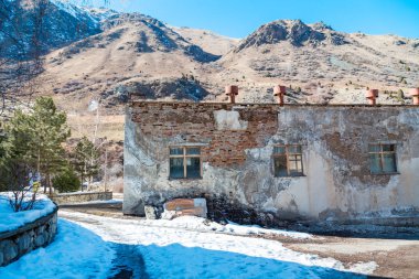 Terk edilmiş eski bir bina. Kış dağlarının arka planına karşı. Kasvetli manzara.