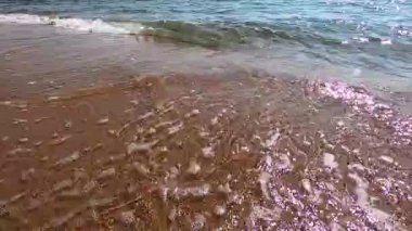 Mavili temiz su dokusu. Kıyı dalgaları ve temiz kum. Okyanusun arka planı ve güneş tarafından aydınlatılan deniz. Doğal arkaplan