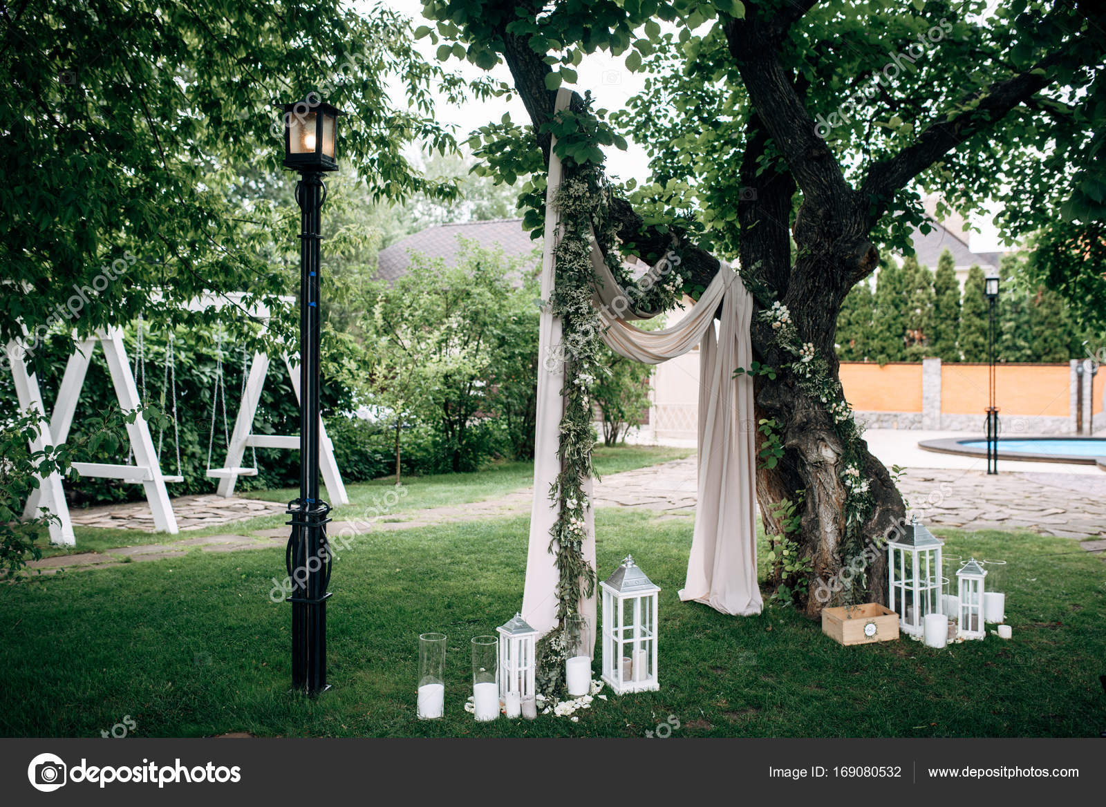 Decorated Area With White Wedding Arch Wooden Candle Lamps And
