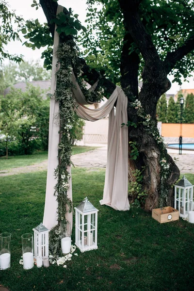 Ingerichte ruimte met witte bruiloft boog houten kaars lampen en bloemen — Stockfoto