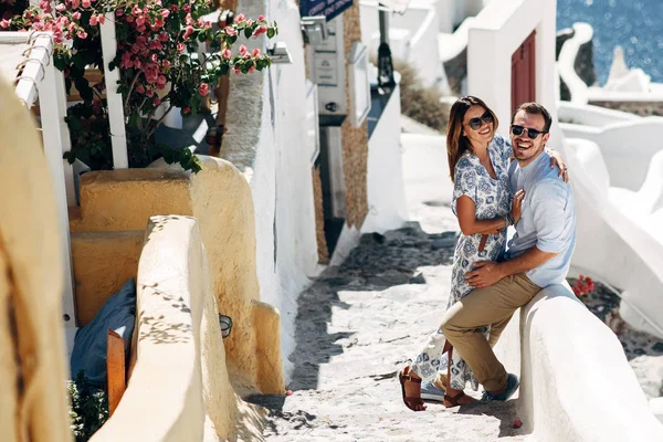 Pareja feliz abrazándose y riendo juntos con una vista de Santorini — Foto de Stock