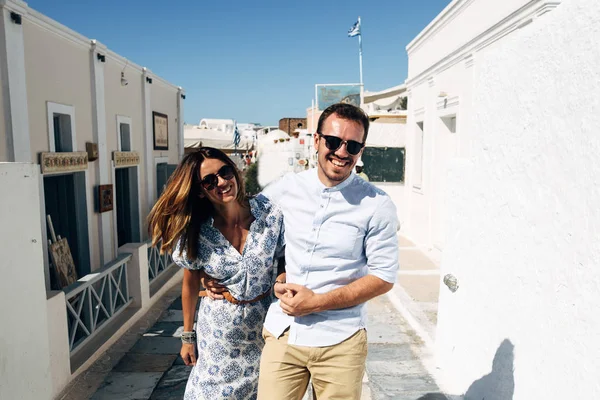 Pareja feliz abrazándose y riendo juntos con una vista de Santorini — Foto de Stock