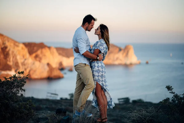 Joven feliz pareja al atardecer abrazándose en terreno rocoso —  Fotos de Stock