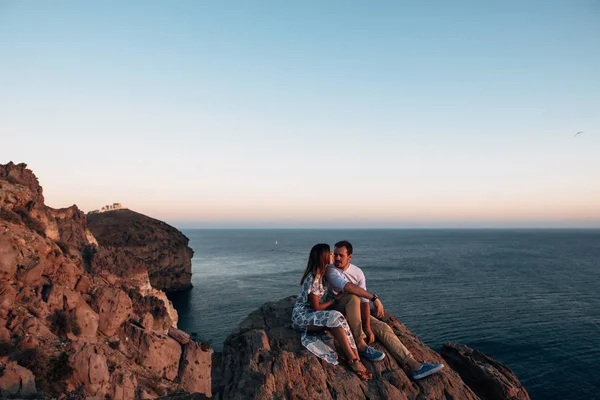 Joven feliz pareja al atardecer abrazándose en terreno rocoso —  Fotos de Stock