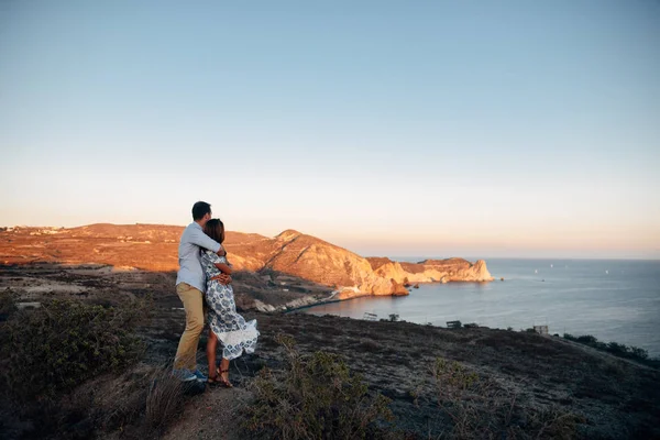 Joven feliz pareja al atardecer abrazándose en terreno rocoso — Foto de Stock