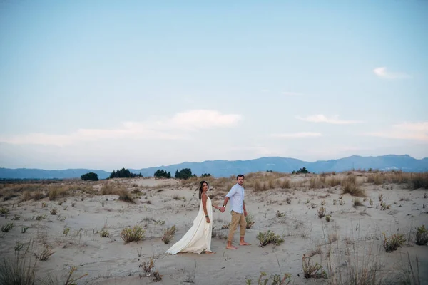 Красивая пара ходьба, держась за руки на песке — стоковое фото