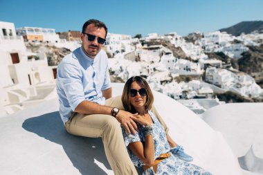 Çift Santorini'de, sarılma ve gülüyor çatıda oturuyor