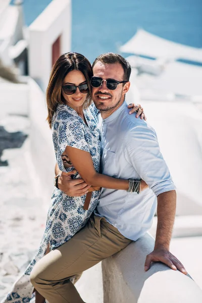 Pareja feliz abrazándose y riendo juntos con una vista de Santorini —  Fotos de Stock