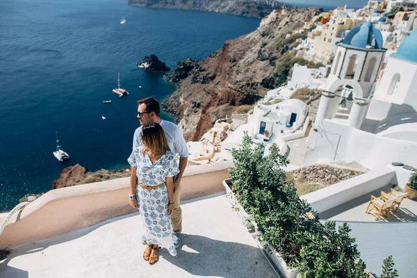 Pareja feliz abrazándose y riendo juntos con una vista de Santorini — Foto de Stock