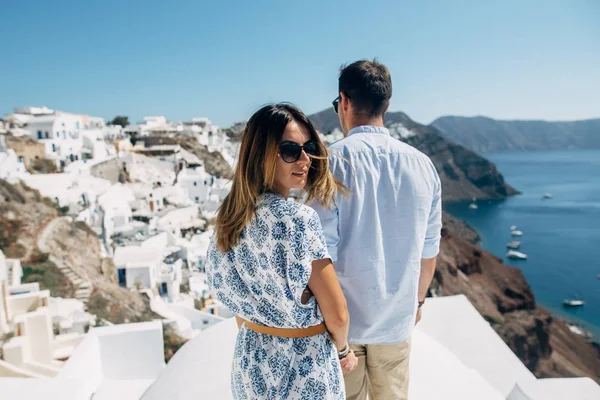 La pareja está de pie en el techo en Santorini, la chica se volvió a la cámara — Foto de Stock