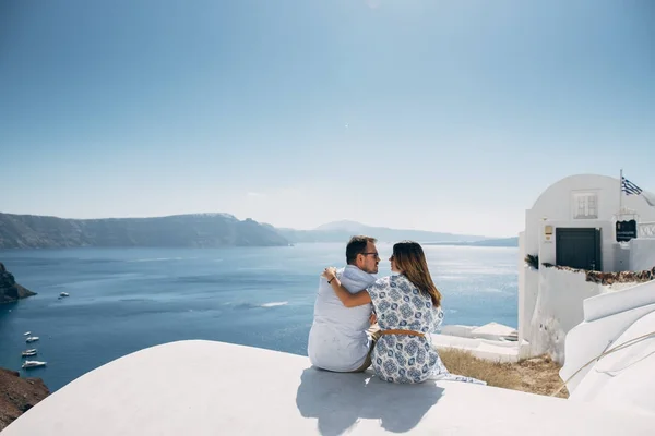 La pareja está sentada en el techo de Santorini, abrazando y riendo — Foto de Stock