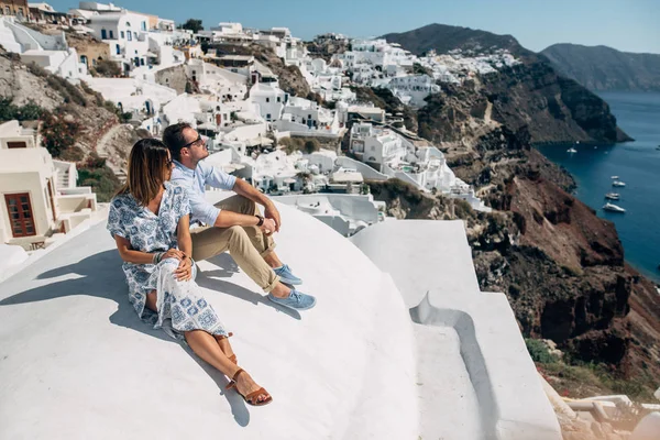 La pareja está sentada en el techo de Santorini, abrazando y riendo — Foto de Stock