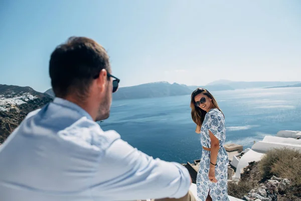 La pareja está de pie en el techo en Santorini, la chica se volvió a la cámara — Foto de Stock