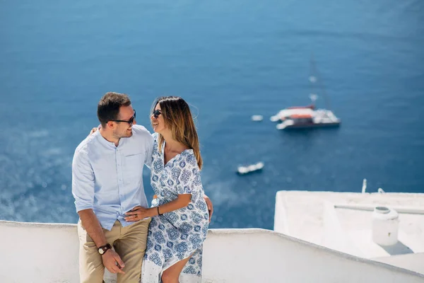 Pareja feliz abrazándose y riendo juntos con una vista de Santorini —  Fotos de Stock
