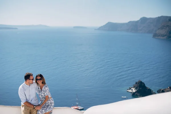 Pareja feliz abrazándose y riendo juntos con una vista de Santorini —  Fotos de Stock