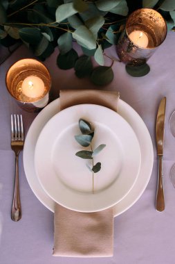 Beyaz ahşap mum lambalar ve çiçekler, çatal ve bıçak ve makara plaka yanında iki kişilik bir düğün masa süslenmiş