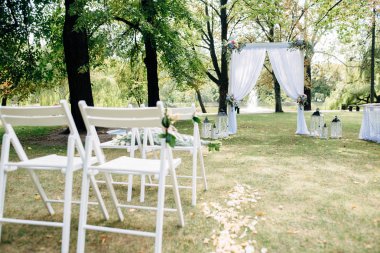 Açık hava düğün töreni, çiçekler ve kurdeleler stand satırlar halinde arka plan üzerinde çim, Beyaz kemer ile dekore edilmiş koltukları