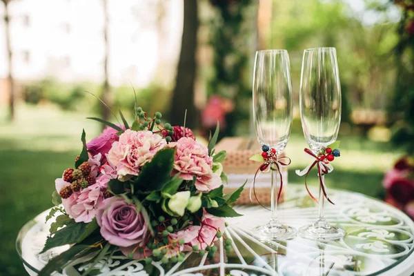 Buquê de noiva com flores roxas e dois copos na mesa redonda branca — Fotografia de Stock