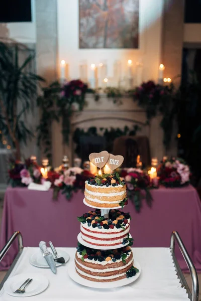 Γυμνή τριών επιπέδων γαμήλια τούρτα με βατόμουρα, σμέουρα και μούρα, δύο πλάκες μορφή καρδιά στην κορυφή — Φωτογραφία Αρχείου