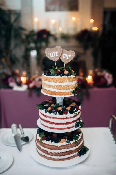 Γυμνή τριών επιπέδων γαμήλια τούρτα με βατόμουρα, σμέουρα και μούρα, δύο πλάκες μορφή καρδιά στην κορυφή — Φωτογραφία Αρχείου