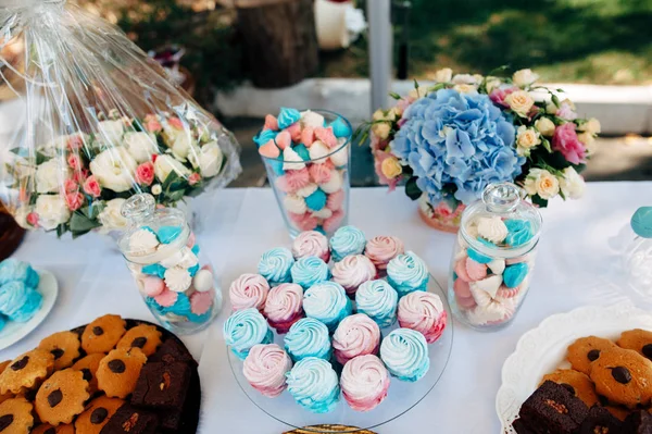 Μπλε και ροζ καραμέλες, μπισκότα και γλυκά και λουλούδια σε έναν πίνακα — Φωτογραφία Αρχείου