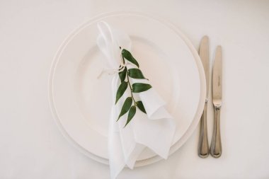 Tabaklar, bıçak, çatal ve buket beyaz çiçek ve yeşillik Merkezi ile tablolarla dekore edilmiş